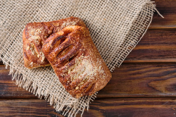 Puffs with cherry jam on burlap on a wooden background. Rustic style