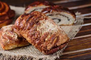 puff buns with jam and raisins in the shape of a snail on burlap and wooden background. Close-up