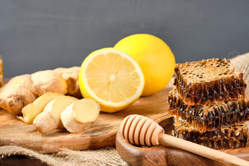 honey in honeycombs on a wooden plate and honey with nuts with lemon and ginger in rustic style on a wooden background. Close-up
