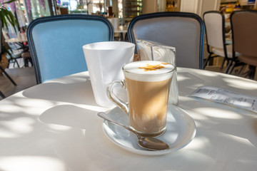coffee latte in glass with frothy milk on table in cafe, Italian style