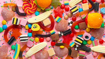 candies with jelly and sprinkles colorful array of different childs sweets and treats over pink like festive background, panorama