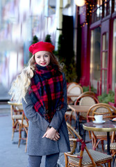 young girl in a red beret and a gray coat near a cafe