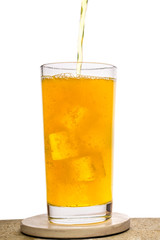 pouring fresh drink yellow soda with ice cubes in glass isolated on white background, concept of refreshing summer drink
