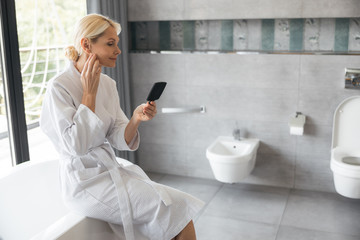 Attentive woman looking at her little mirror