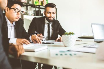 A team of young businessmen working and communicating together in an office. Corporate businessteam and manager in a meeting.