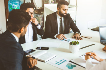 A team of young businessmen working and communicating together in an office. Corporate businessteam and manager in a meeting.