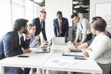 A team of young businessmen working and communicating together in an office. Corporate businessteam and manager in a meeting.