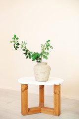 beautiful bouquet of green twigs with leaves stands in vase on wooden table in the living room. Home interior. Scandinavia. Rustic. Flower composition. Modern plant in a ceramic vase. Eco furniture