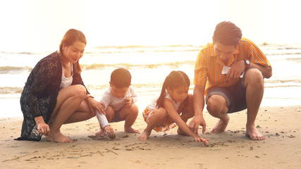 Young family sitting and play the sand on the beach