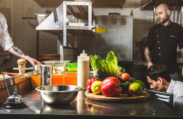 Professional chef cooking in the kitchen restaurant at the hotel, preparing dinner. A cook in an apron makes a salad of vegetables and pizza.