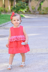 portrait of little girl in red dress walking in the park