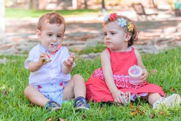 twin brothers playing in the park. Little girl drinking water with her bottle of water.