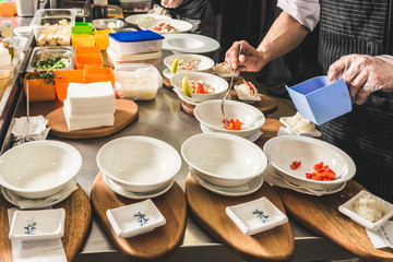 Professional chef cooking in the kitchen restaurant at the hotel, preparing dinner. A cook in an apron makes a salad of vegetables and pizza.