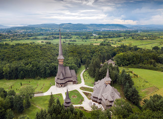 Aerial panoramic view of traditional ancient Maramures wooden orthodox church in Transylvania with highest wooden belltower in Europe, Romania. UNESCO world heritage site.