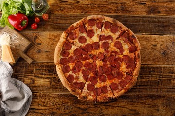 Pepperoni pizza on a wooden table. Still life with ingredients.
