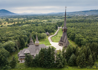 Aerial panoramic view of traditional ancient Maramures wooden orthodox church in Transylvania with highest wooden belltower in Europe, Romania. UNESCO world heritage site.