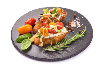 Bruschetta with cottage cheese, tomatoes, champignon mushrooms, garlic and herbs. Spanish Tapas and Pinchos on a stone plate, isolated on white background