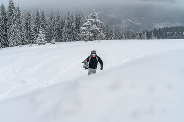 Fototapeta na wymiar Snowboarder goes up to snow hill. Mountain freeride snowboarding. Winter Carpathians