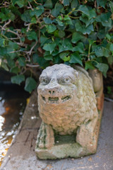 kleine Figur auf einer Mauer unter Farn