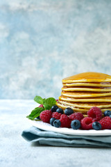 Homemade hot pancakes with maple syrup and fresh berries.