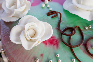 whitening a rose from the icing on the wedding cake against the background of chocolate and green-pink icing