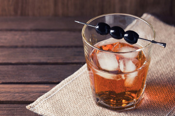 Glass of alcohol drink with olives on pick