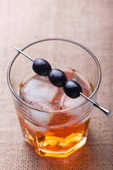 Glass of alcohol drink with olives on pick