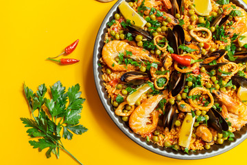 pan with spanish paella with seafood on a yellow background, top view - 292705194
