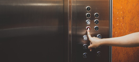 Close up woman pressing button 1st floor inside elevator.