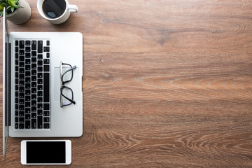 Wood office desk table with white smartphone with blank mock up screen, laptop computer, cup of...