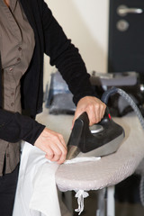 Close-up Of woman Ironing Clothes On Ironing Board