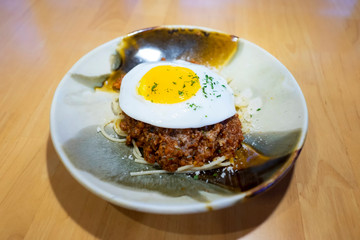 Italian spaghetti topped with a fried egg and ground beef bolognese sauce.