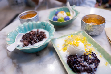 Thai traditional sweet dessert on marble table. Soft sweet sticky rice with coconut milk ice cream and sweet sticky corn pudding. 