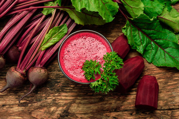 Top view of fresh beet juice with parsley from organic farm in a glass on a wooden rustic table.