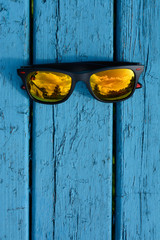sunglasses on a floral background with a blue bench