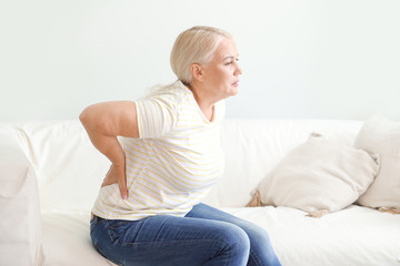Mature woman suffering from back pain at home