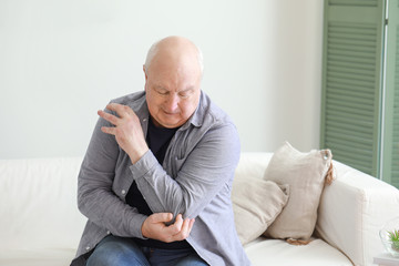 Senior man suffering from pain in elbow at home