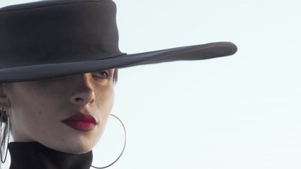 Gorgeous red lipped woman wearing black hat looking away thoughtfully. Beautiful woman wearing red lipstick and black hat posing outdoors gracefully