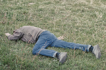 The corpse of a tramp in the grass. Criminal. Alcoholic intoxication. Killing a homeless man. dead...