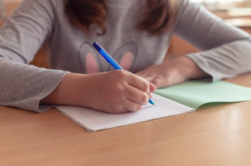 hand of a teenage girl writes with a ballpoint pen in a terad during a lesson at school