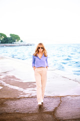 Fototapeta na wymiar Smiling beautiful woman walking on the beach promenade in a small town