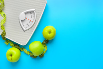 Scales, apples and measuring tape on color background. Weight loss concept