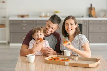 Happy family eating pizza at home