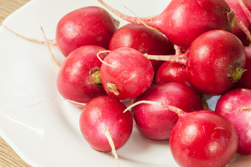 Red radish lies on a plate on the table