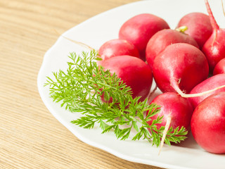 Red radish lies on a plate on the table