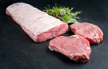 Roher dry aged Kalbsrücken mit Kräutern angeboten als closeup auf schwarzen Hintergrund mit...
