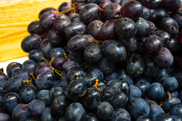 Spoiled black grapes. Rotten grape berries. Selling spoiled fruit. The grape juice. Overripe grape berries.Pile of discarded rotten grapes. Concept of spoiled harvest with copy space.