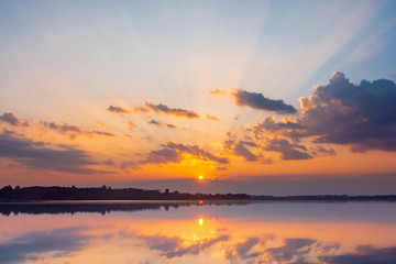 Naklejka na ściany i meble Sunset reflection lagoon. beautiful sunset behind the clouds and blue sky above the over lagoon landscape background. dramatic sky with cloud at sunset.