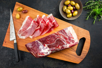 Traditioneller luftgetrockneter Parma Schinken mit Kräutern und Oliven angeboten als Draufsicht...