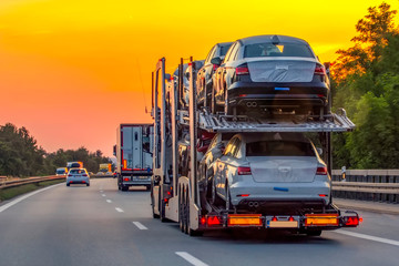Naklejka premium Truck trailer transports new cars rides on highway,